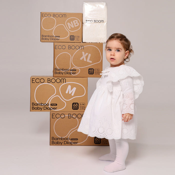 Niña de pie junto a cajas Eco Boom de las tallas NB, M, L y XL